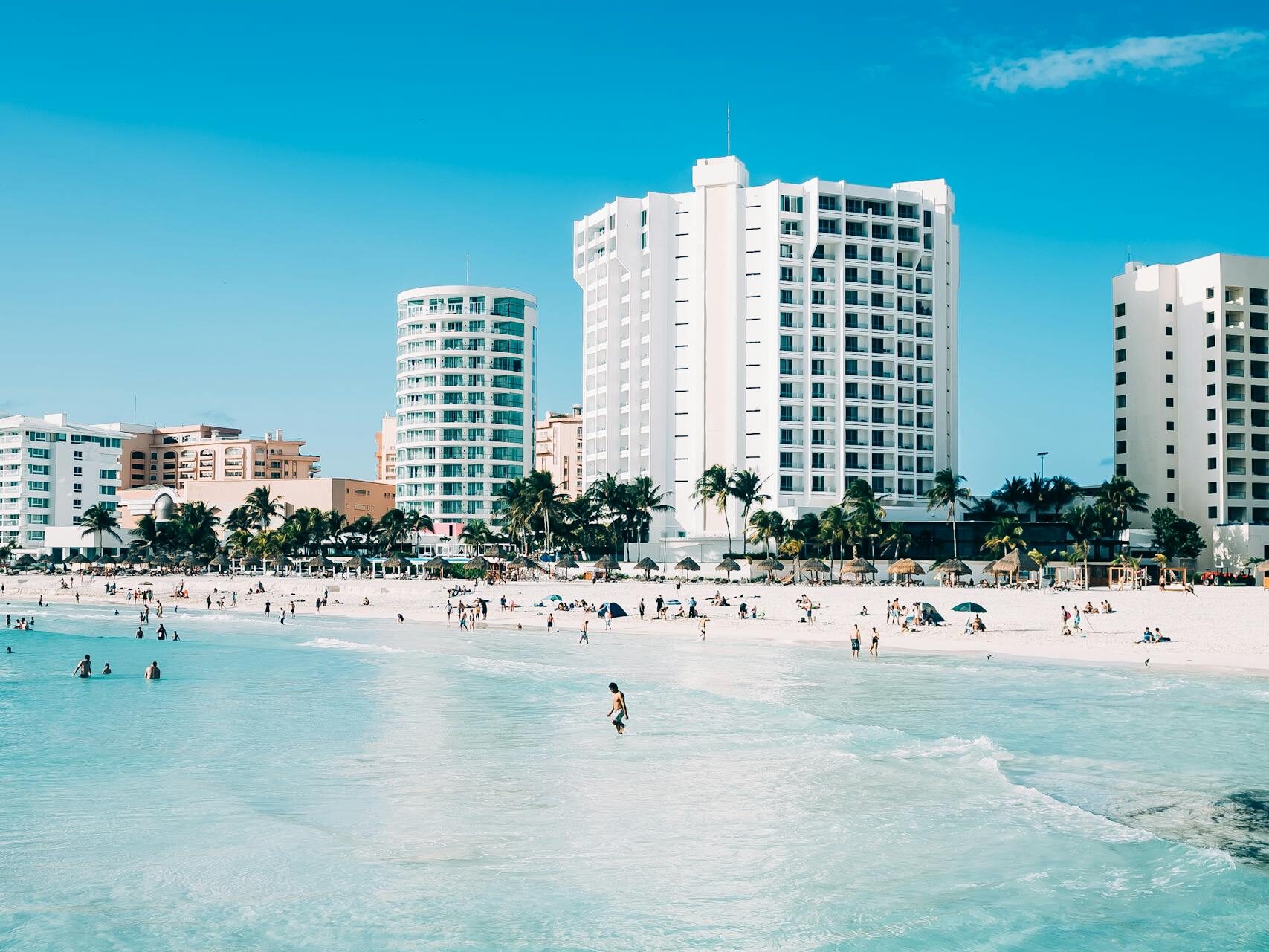 Scenic view of modern hotels along the beachfront in Cancun, Mexico, with clear blue waters.