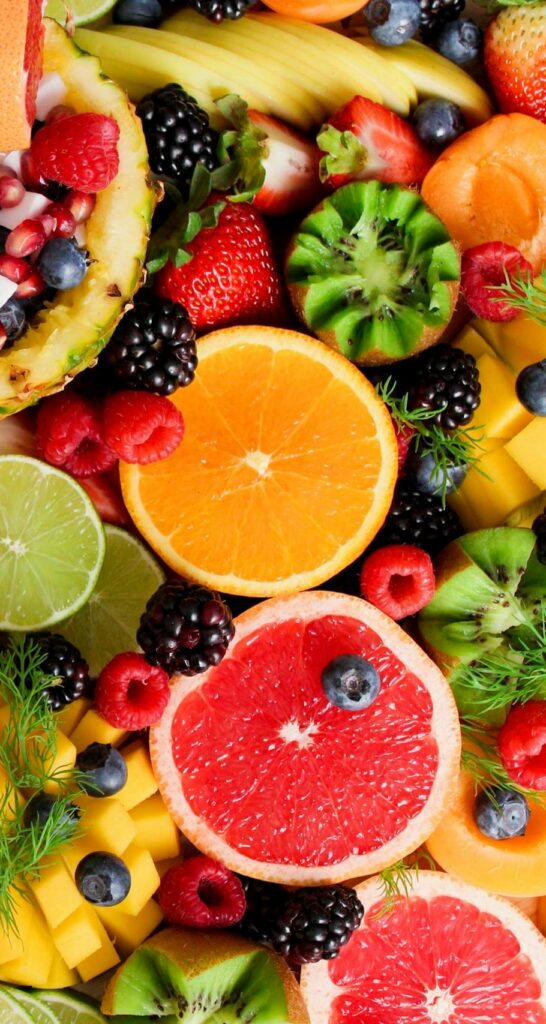 Colorful flat lay of assorted tropical fruits including pineapple, berries, and citrus.